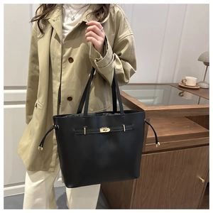 Detail of a black leather tote bag with gold twist lock and belt decor on a model