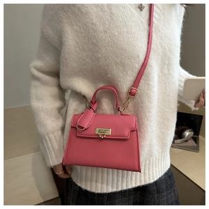 Dettaglio borsa in pelle rosa con chiusura a cuore dorata e tracolla sottile inclusa