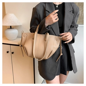 Close-up of khaki leather tote bag with pleated side details and slender handles
