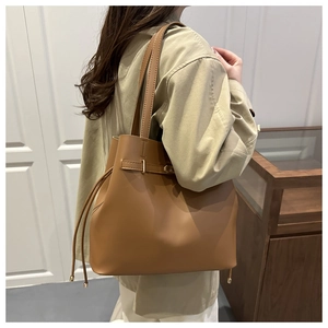 Detail view of large vintage brown leather bucket bag with golden buckle and drawstrings