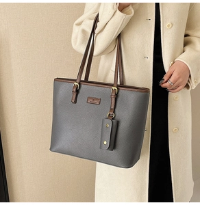 Detail of grey pebbled leather tote bag with brown handles and small hanging pouch