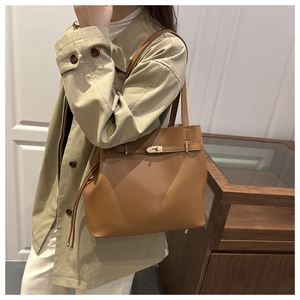 Detail of the brown leather bucket bag showing metal lock and protective base feet