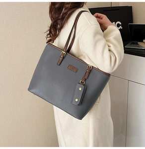 Detail of grey pebble leather tote with brown handles and gold hardware on shoulder