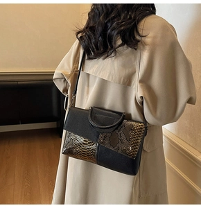 Detail view of snakeskin textured handbag on model showing high-end metallic finish