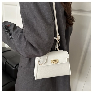 Detail der weißen Handtasche aus Leder mit goldener Schließe und rundem Anhänger-Dekor