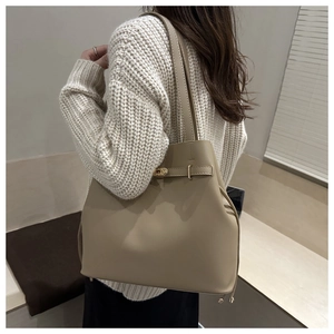 Detail of beige bucket bag featuring a gold rotating lock and matte textured surface