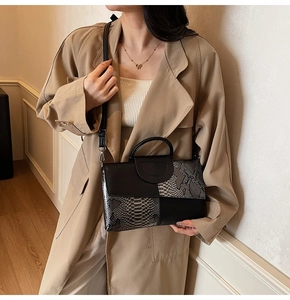 Detail of snake skin pattern and lychee leather on a chic color-blocked handbag