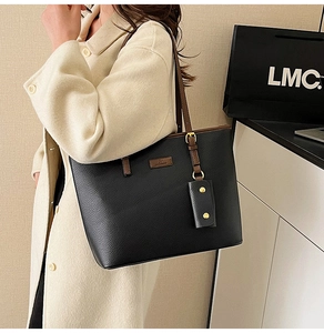 Detailed side view of black lychee texture tote bag with brown straps on model