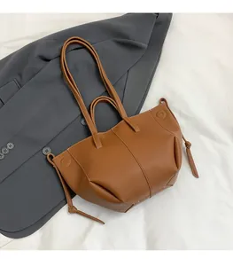 Gros plan d'un sac cabas en cuir marron à motif litchi avec détails à cordon et bandoulière
