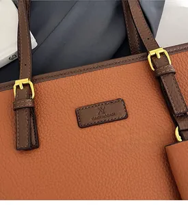 Detail of brown pebbled leather tote bag featuring golden metal buckle and fine stitching