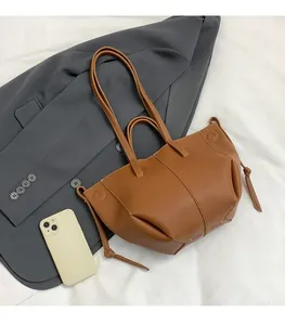 Détail d'un sac cabas marron en cuir grainé avec un smartphone pour comparer la taille