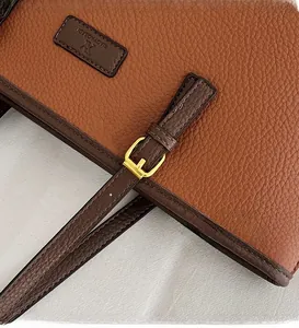 Detail of brown lychee grain leather tote with gold adjustable buckle and stitching