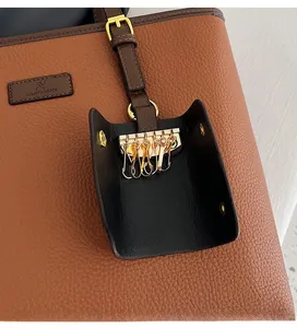 Detail of brown lychee grain leather tote bag with external black key pouch and gold hook