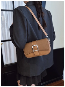 Détail d'un sac bandoulière marron en patchwork avec boucle argentée porté par un modèle