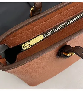 Detail of smooth golden zipper hardware on brown pebble grain leather tote bag