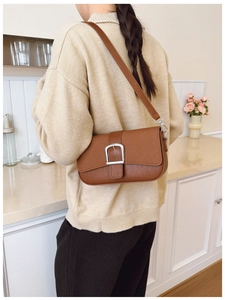 Détail du sac à bandoulière marron avec boucle argentée porté par un mannequin femme