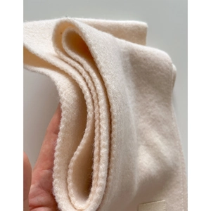 Macro detail of thick cream knitted fabric showing the warm texture and premium material