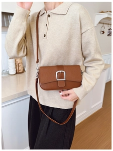 Gros plan d'un sac à bandoulière vintage marron avec boucle carrée argentée sur modèle