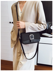 Détail d'un sac bandoulière minimaliste en cuir noir avec boucle métallique argentée