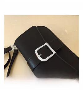 Détail de la boucle argentée en D sur un sac bandoulière en nylon noir à texture fine