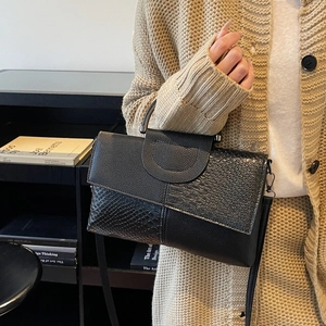 Women's black mixed-texture snakeskin handbag with metal handle and crossbody strap