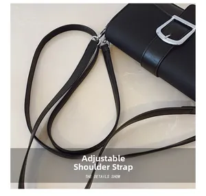 Détail de la bandoulière réglable et boucle en métal argenté sur un sac noir texturé
