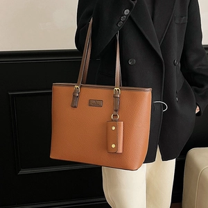 Brown leather tote bag with small pendant pouch and gold hardware on shoulder