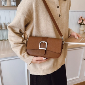 Sac à bandoulière rétro marron caramel avec boucle argentée dans un décor intérieur