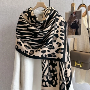 Thick leopard and zebra print shawl with tassels draped over a coat for winter warmth