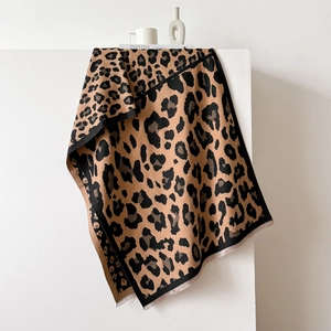 Detail view of leopard print scarf featuring black stitched edges and soft short tassels