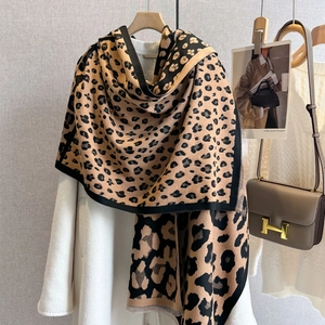 Close-up of leopard print cashmere scarf with fine tassel hem on a white wool coat