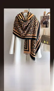Detail of winter scarf featuring leopard print, soft cashmere-like texture and fringed edge