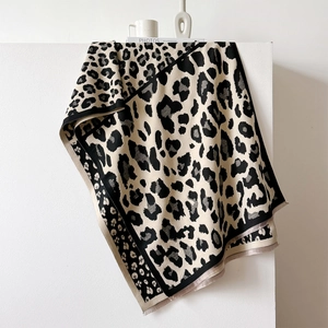 Detail of leopard print scarf with dotted borders and fringe trim on a display stand