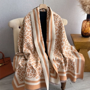 Detail of leopard print scarf featuring striped edges and tassels on an armchair