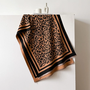 Detail of leopard print scarf featuring black stitched edges and fine short tassels