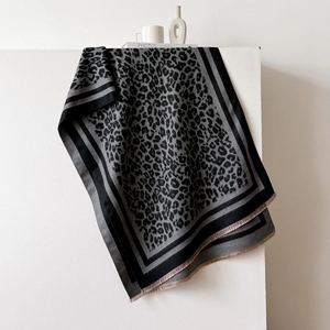 Detail of leopard print scarf featuring striped borders and soft tassel fringes