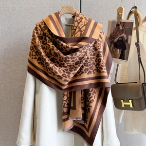 Close-up of leopard print scarf with fine fringe detail and handmade label on white coat