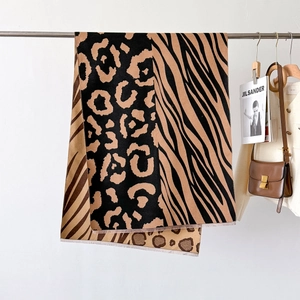 Thick leopard and zebra print cashmere-feel shawl with tassels hanging on a hanger