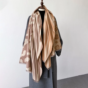 Close-up of leopard print cashmere feel shawl with fringe details on a grey coat
