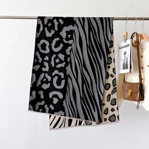 Detail view of leopard and zebra print scarf with fine tassels on a metal rack