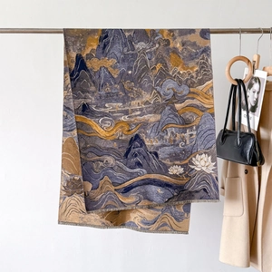 Detail of blue and gold Jacquard scarf featuring traditional Chinese landscape and tassels
