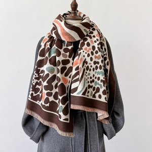 Detail of leopard print thick cashmere-like shawl with fringes on a grey wool coat