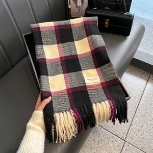 Detail eines dicken Strickschals mit Karomuster und Fransen in Schwarz Beige und Weinrot
