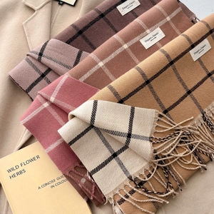 Close-up of checkered cashmere-feel scarves with tassels and elegant woven labels