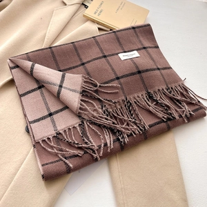 Close-up of thick plaid cashmere-like scarf with fringe details and woven brand label