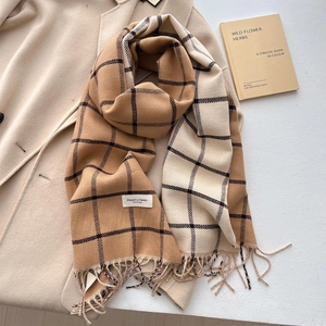 Detail of soft plaid scarf with tassels on beige coat and aesthetic book prop