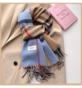 Dettaglio di sciarpa a quadri tipo cashmere con frange su cappotto cammello