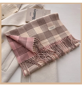 Close-up of pink and brown plaid scarf with fringe tassels on a wool coat