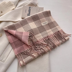 Detail view of pink and beige plaid scarf showing soft fabric texture and fringe trim