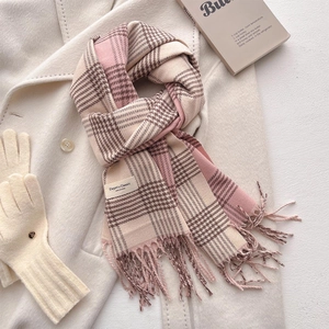 Pink and beige plaid winter scarf with fringe tassels on soft wool coat background